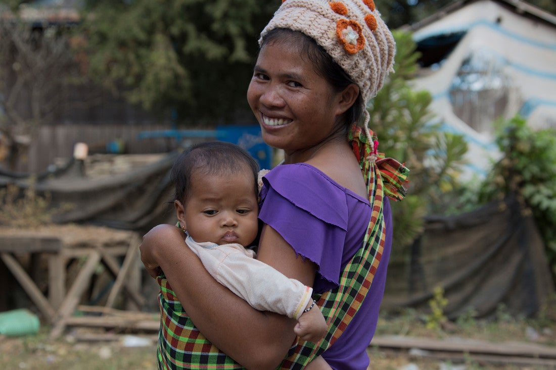 Une femme portant une chemise violette sourit et tient son bébé.