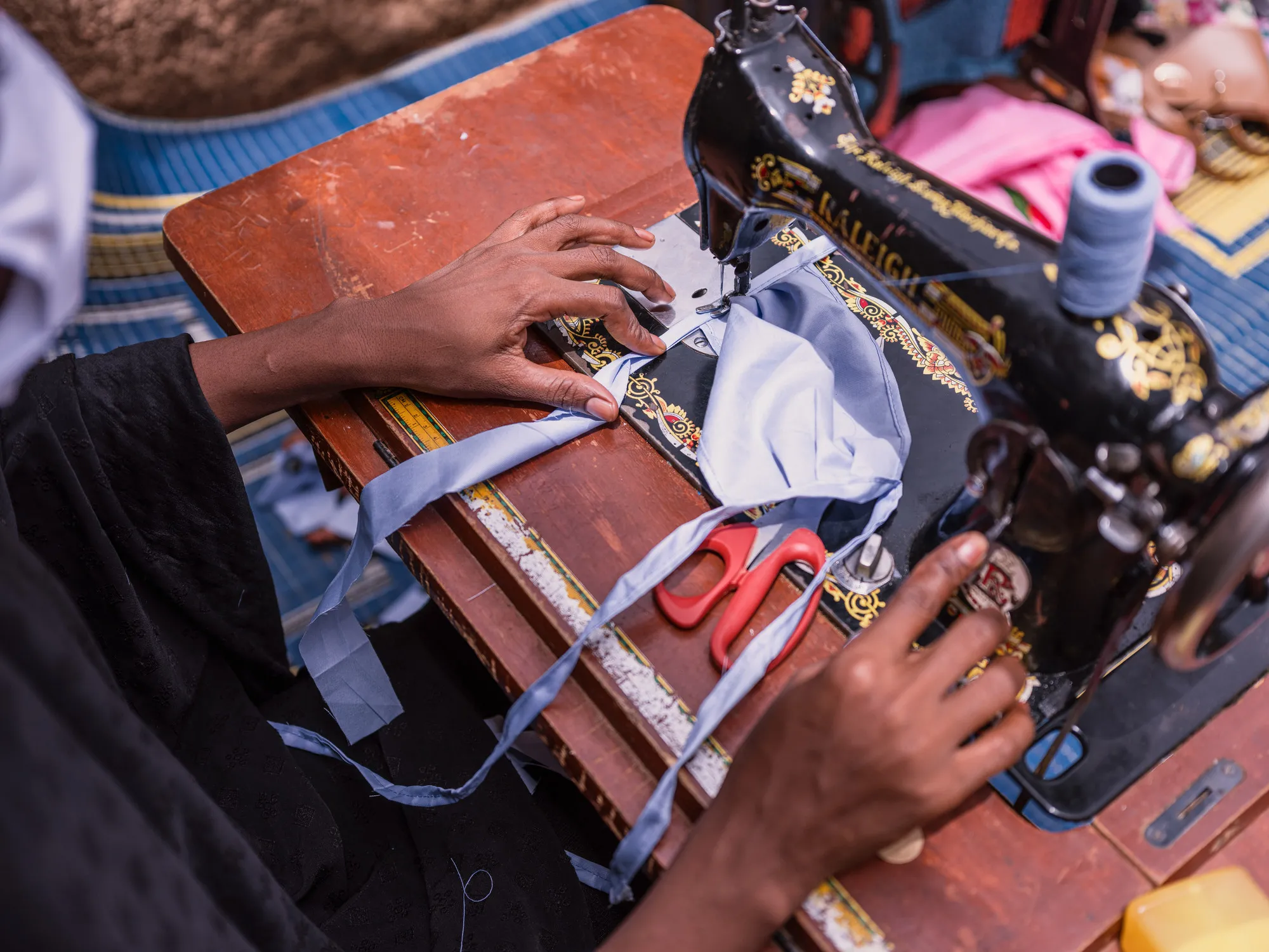 A woman in Niger uses a sewing machine to make a mask.
