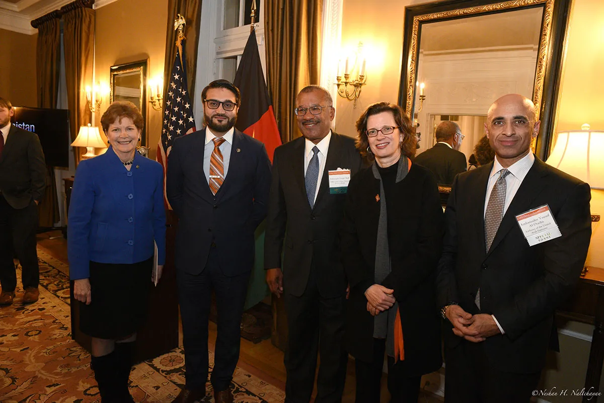 Ambassador Hamdullah Mohib and CARE CEO Michelle Nunn stand with a woman in a blue jacket, and two men in black suits