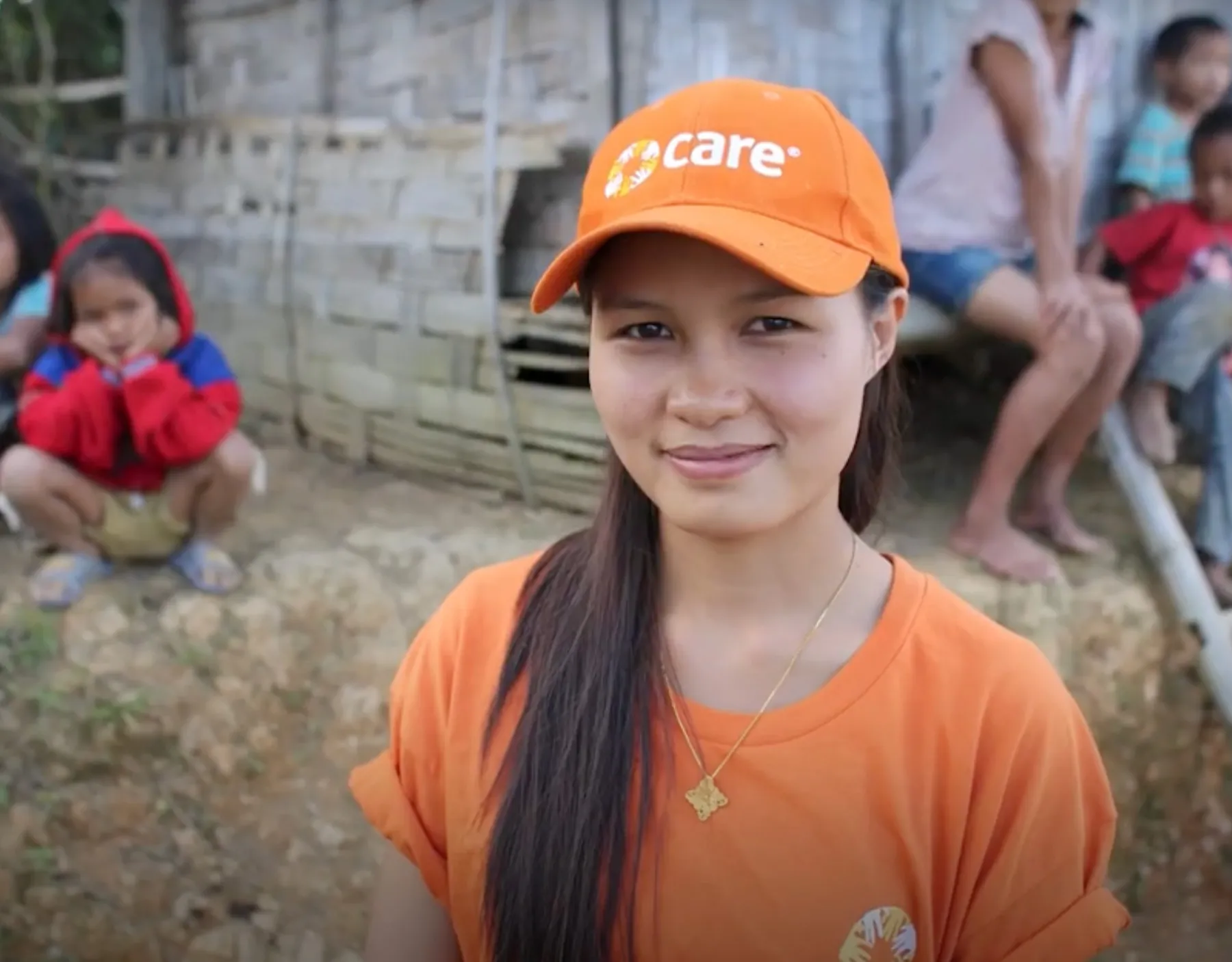 A woman wearing a CARE orange hat and shirt.