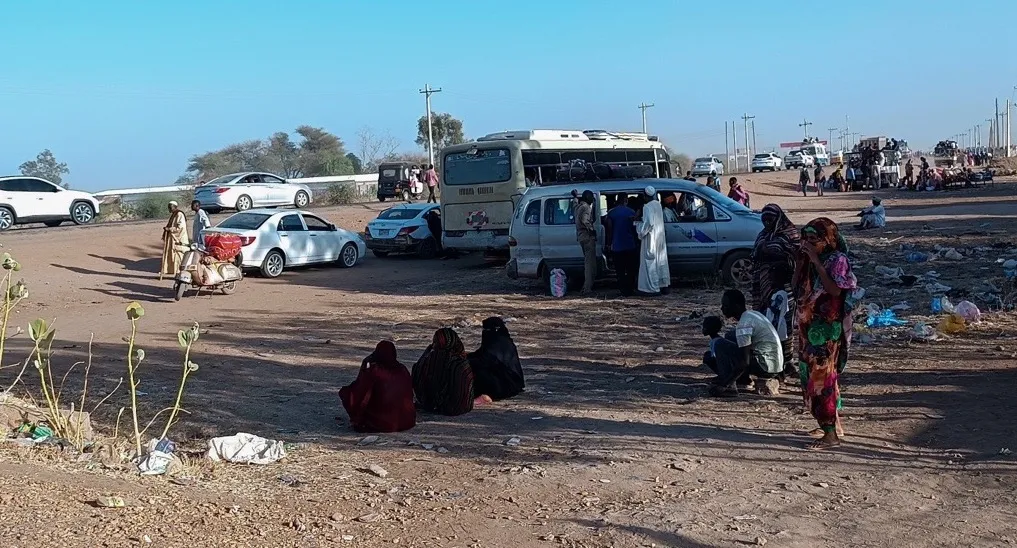 People on the side of the road next to cars and other vehicles
