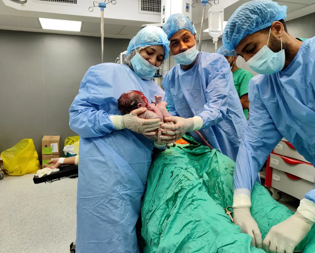 Doctors and nurses hold a newborn in a hospital