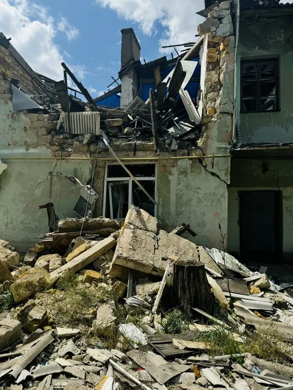 Image of a half-crumbled wall of a two-story home, a pile of rubble in the foreground.