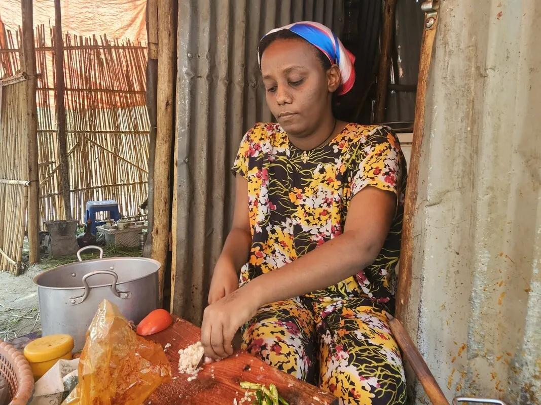 An Ethiopian woman, chopping onions to prepare a meal in her food shop.