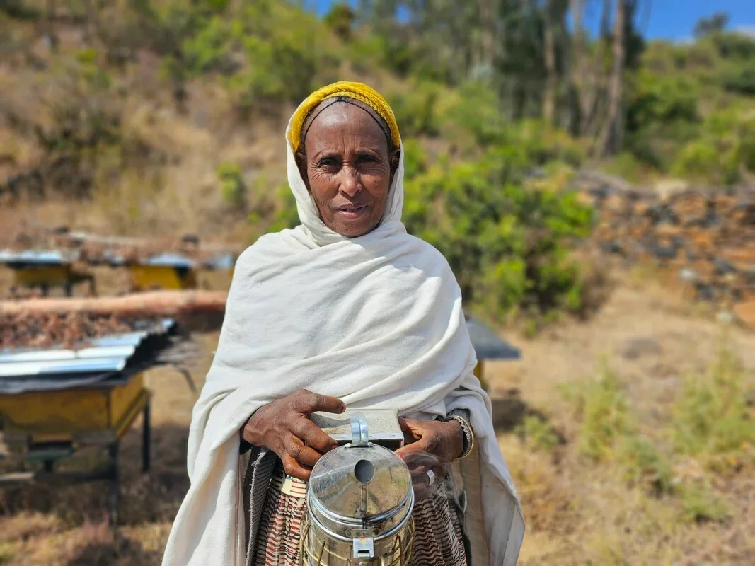 A woman holds a basket and a tin can.