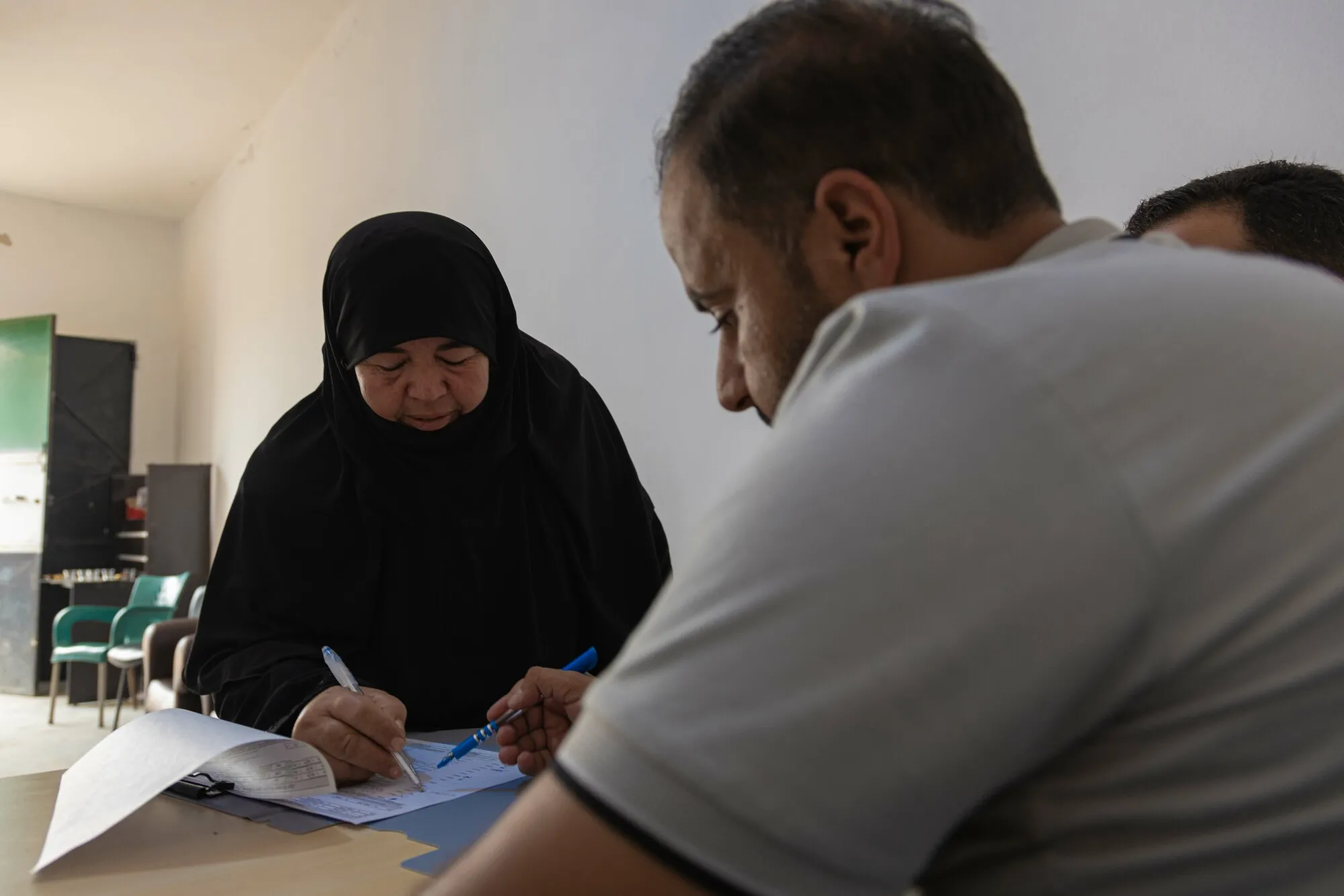 A Syrian woman signs a paper, presumably related to a cash assistance program.