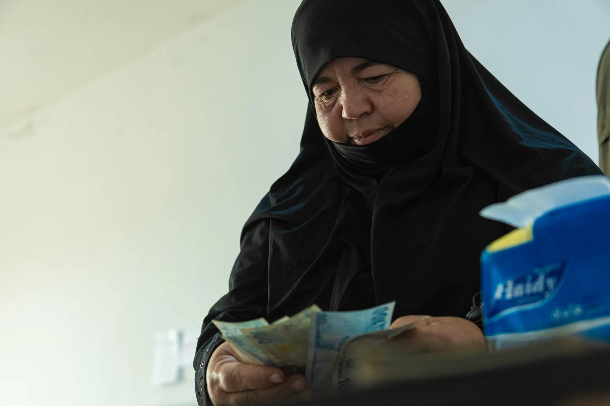 A Syrian woman counts money, likely from a cash assistance program designed to support families in need.