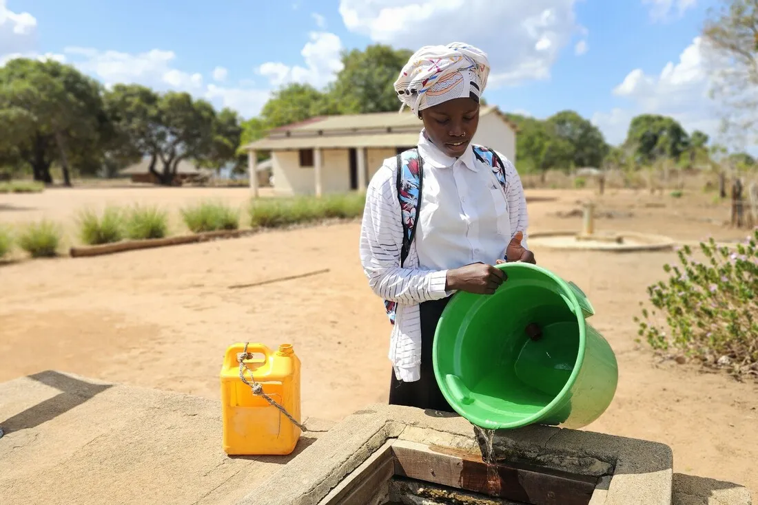 Farsana, a girl from Mozambique, pouring water from a bucket into her school's water tank.