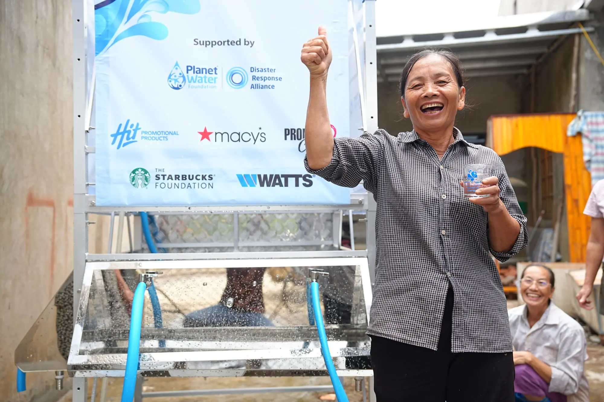 A woman smiles while holding a cup of water.