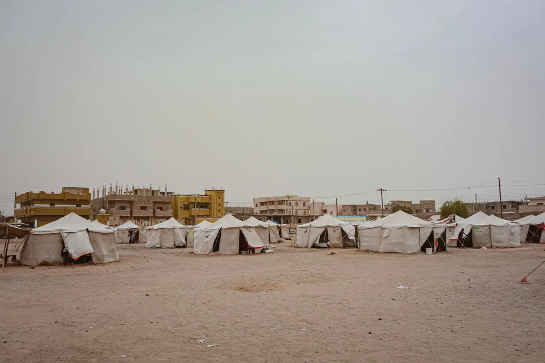 A sandy campsite with several white tents