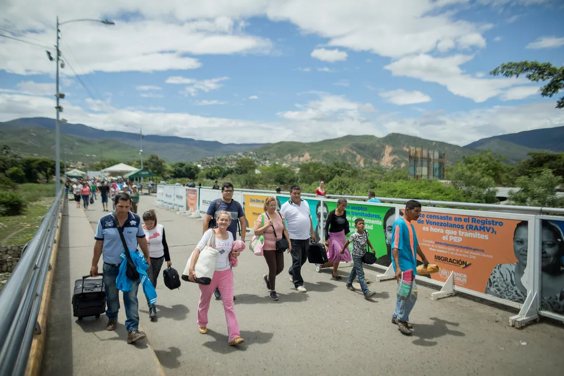 A group of people walk on the side of a highway.