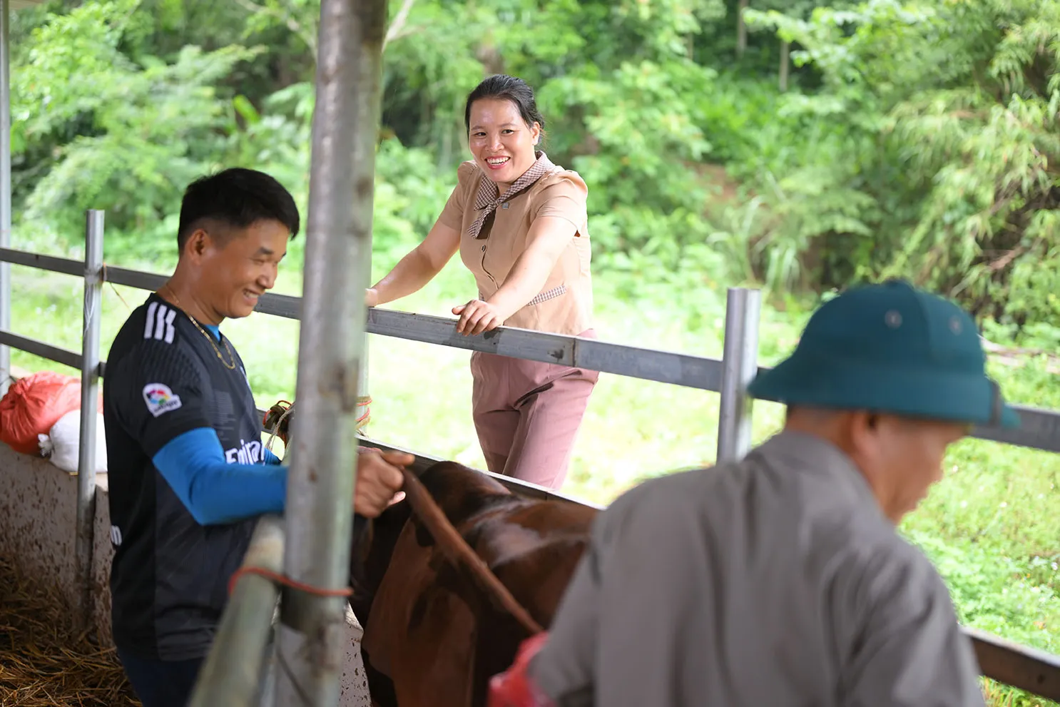 A Vietnamese woman smiles while talking to two men.