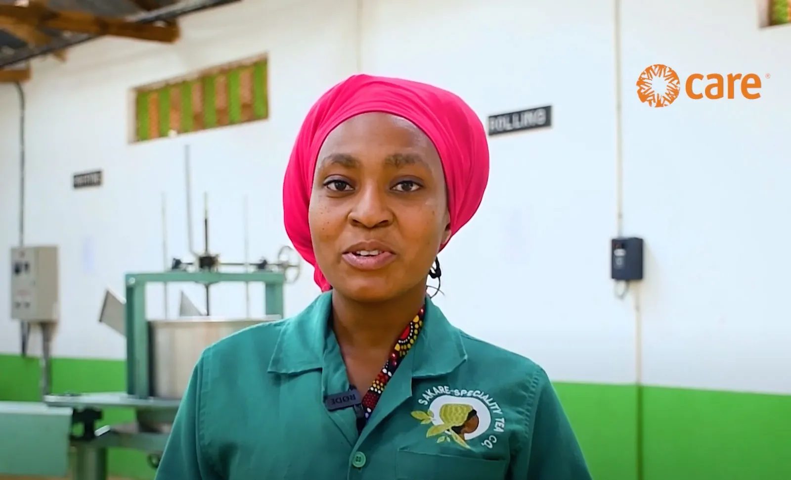 A woman addresses the camera in an indoor warehouse.