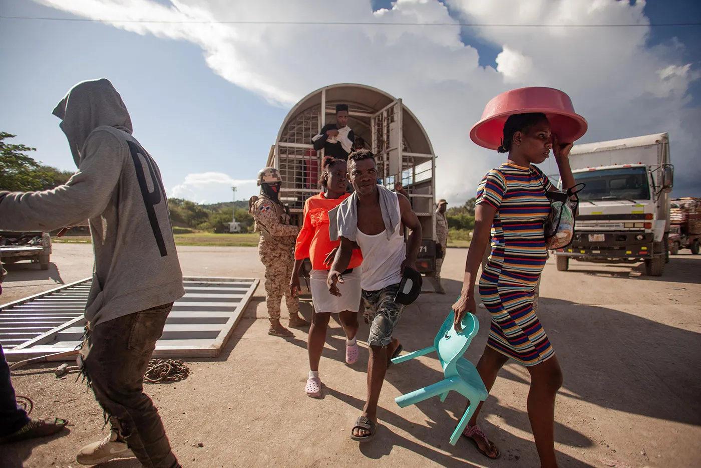 A group of Haitian people disembark from a guarded truck. They are being returned to Haiti from the Dominican Republic.