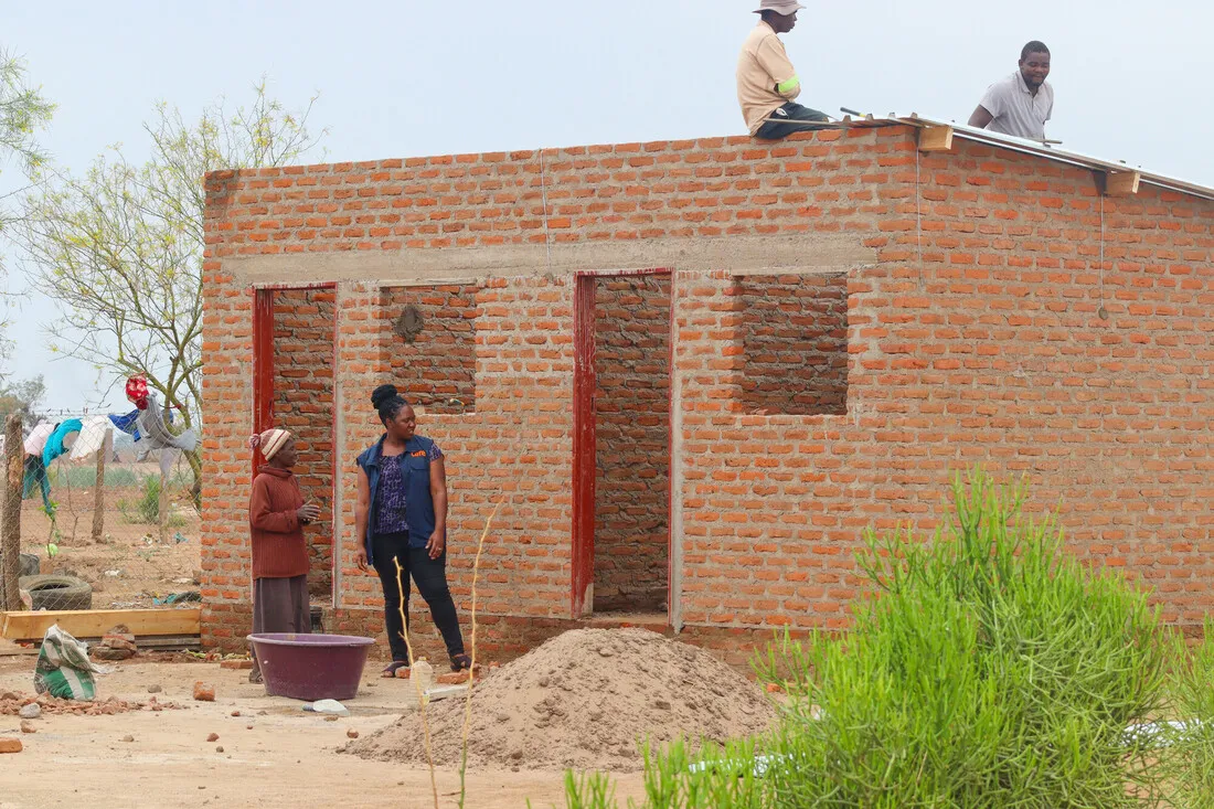 Mwaedza and a CARE staff member oversee the construction of Mwaedza's new home.