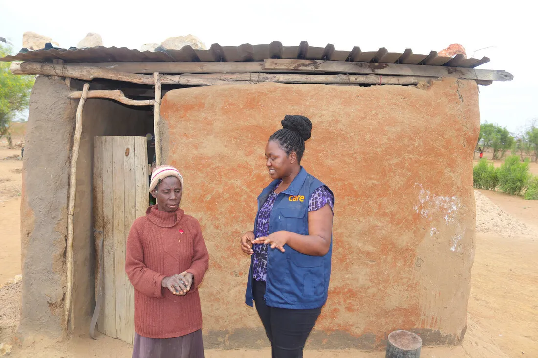 Mwaedza, a Zimbabwean woman, speaks with a CARE staff member outside her home.