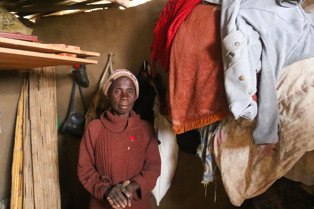 A Zimbabwean woman stands inside her makeshift mud and bamboo home.