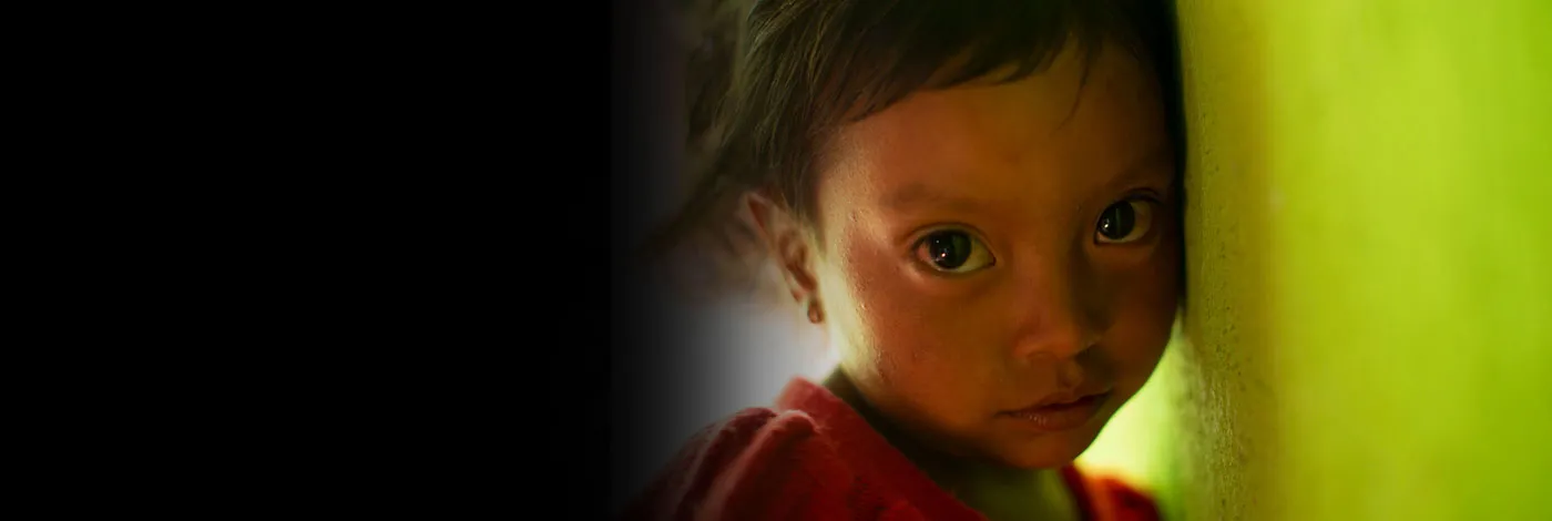 A close-up portrait of a young girl leaning against a wall.