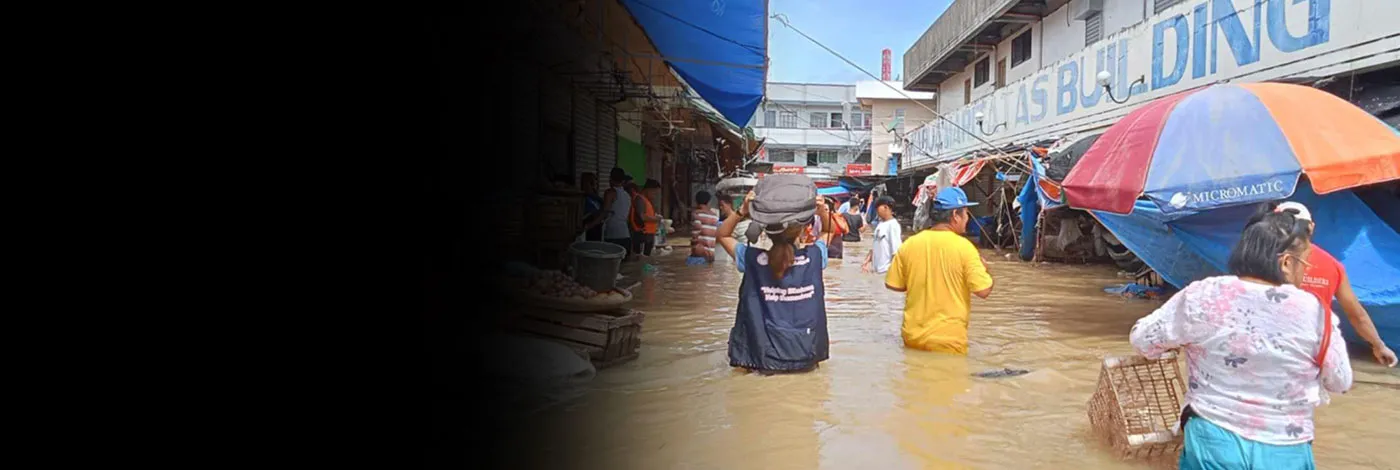 A group of people wade through hip-deep water carrying supplies.